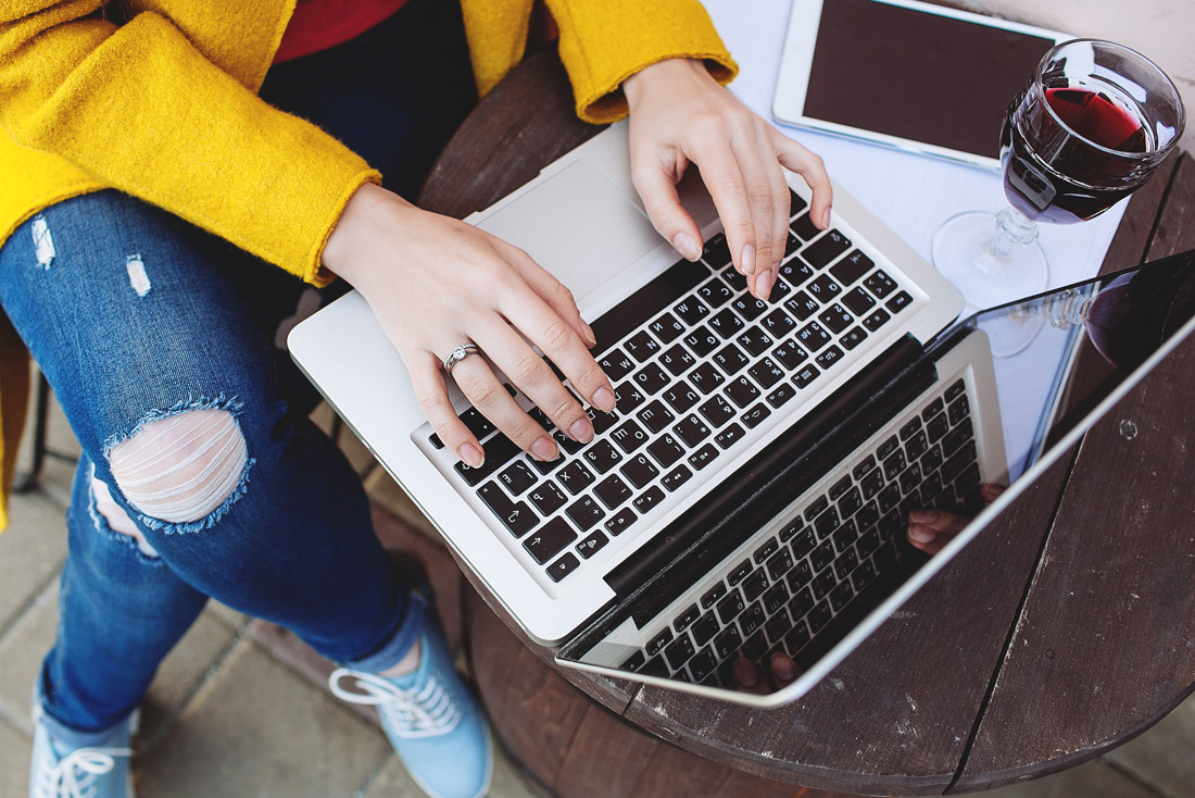 Women typing on laptop with red wine for Zoom games